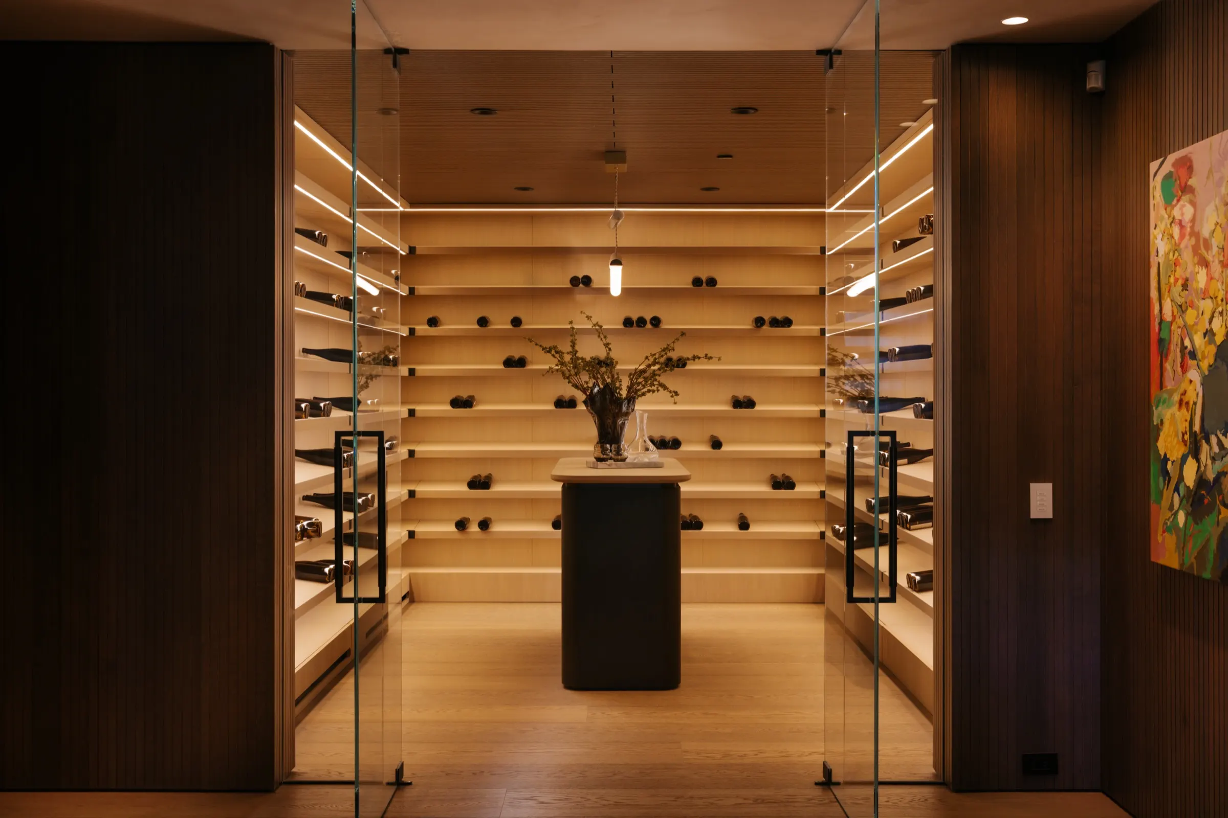The Getty House, Brentwood — wine cellar behind glass doors with backlit oak shelving