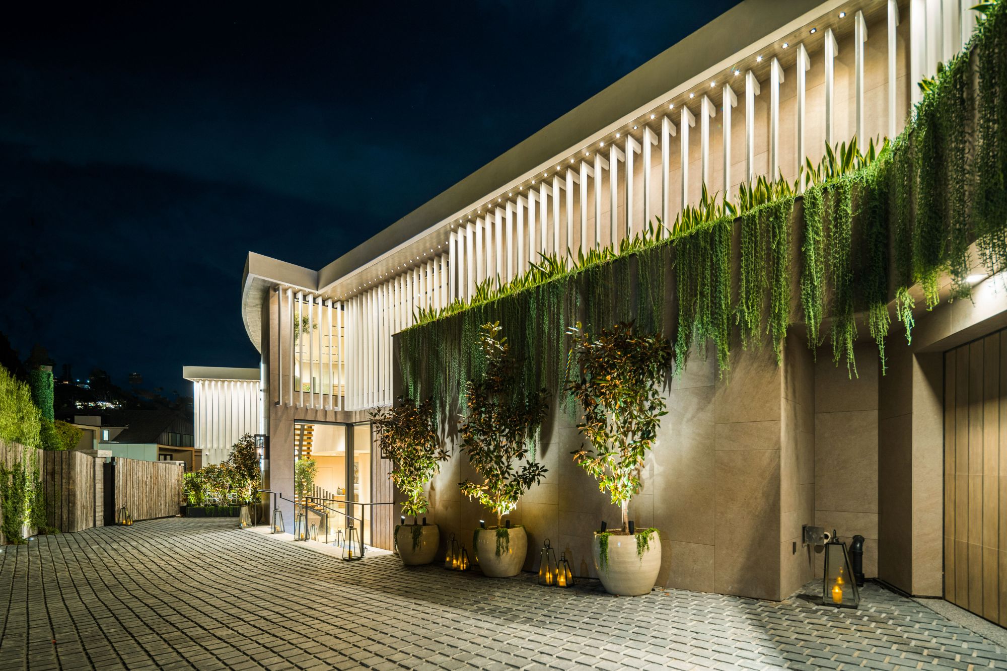 The Flicker Estate entry facade at night with hanging gardens
