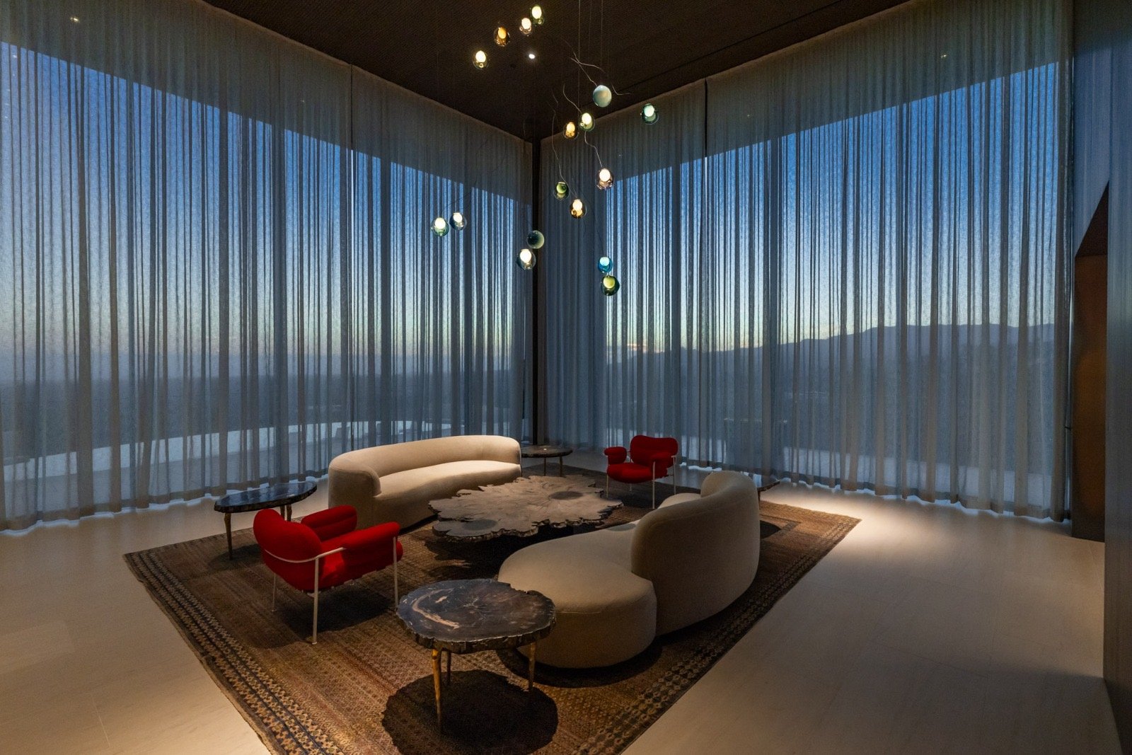 Getty House — lounge with curved sofas and organic chandelier at sunset
