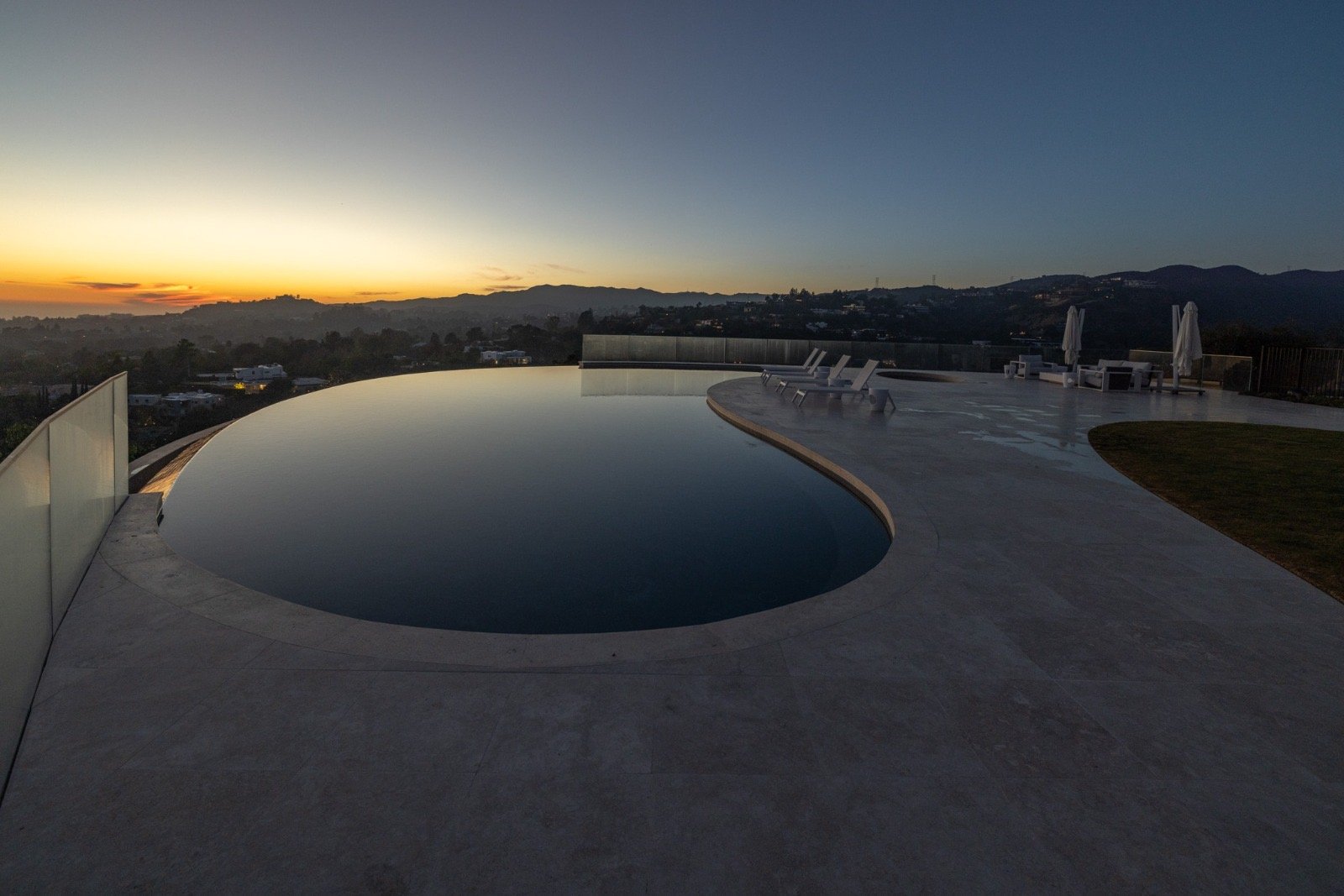 Getty House — infinity pool at dusk, horizon view over the travertine deck