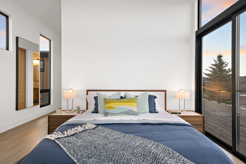Icon Haus — bedroom with wood headboard and sliding glass door to the mountains