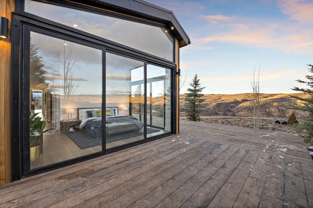 Icon Haus — master suite deck behind a glass wall, hillside beyond