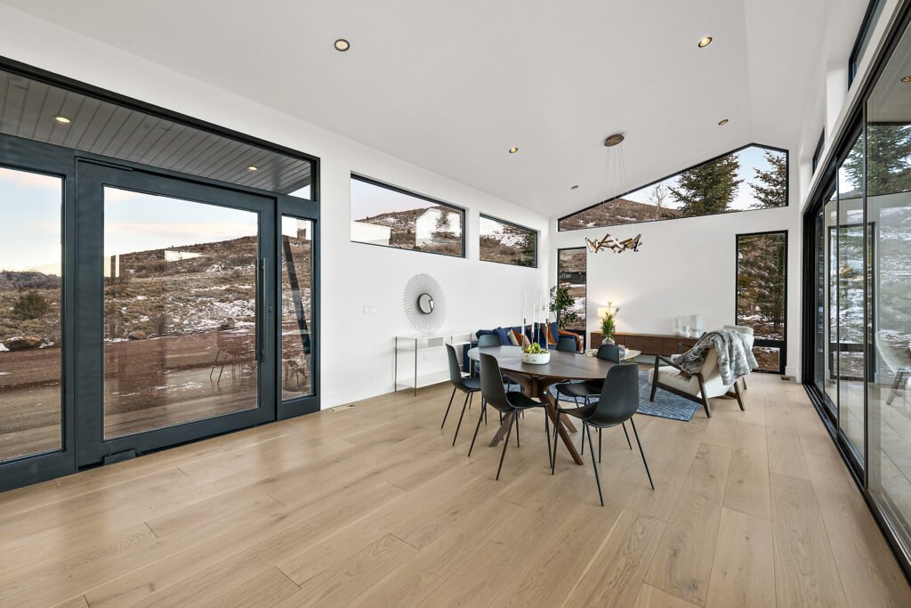 Icon Haus — vaulted dining and living space with black-framed doors and hardwood floors