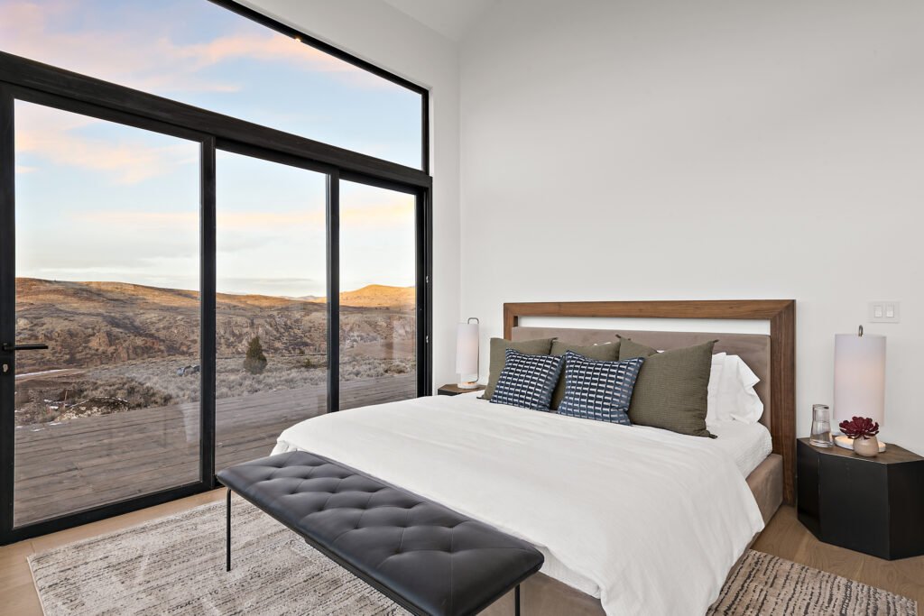 Icon Haus — master suite with wood headboard and sliding glass door to the hillside