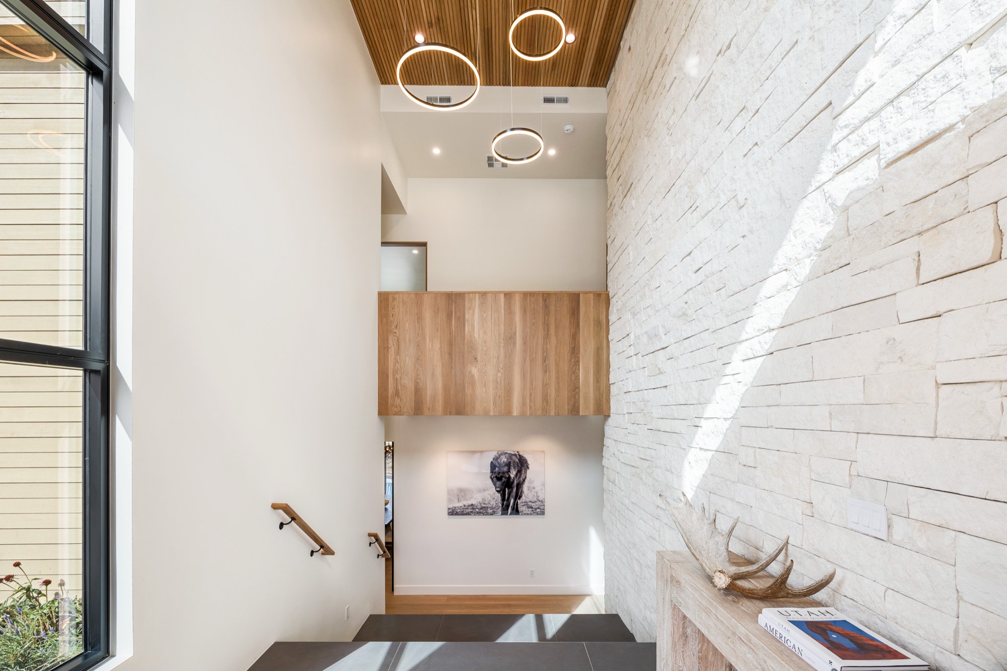 Islay Way — double-height entry stair with limestone wall and wood ceiling