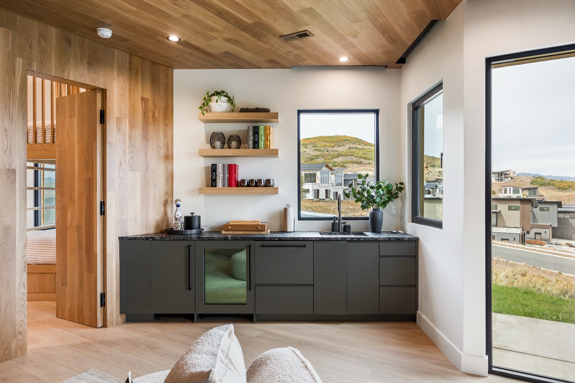 Islay Way — the second kitchen of the dual-kitchen design, deep green cabinetry under a wood ceiling