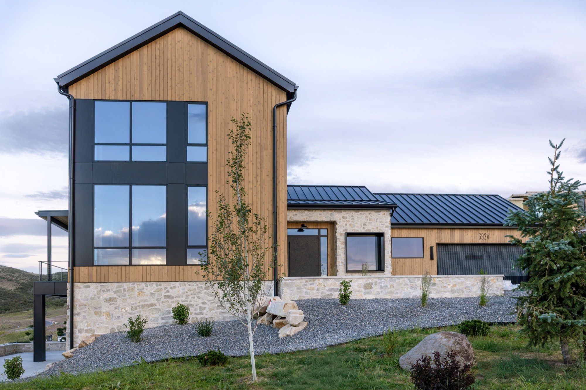Lumen — front gable and drive at dusk with gravel landscape beds