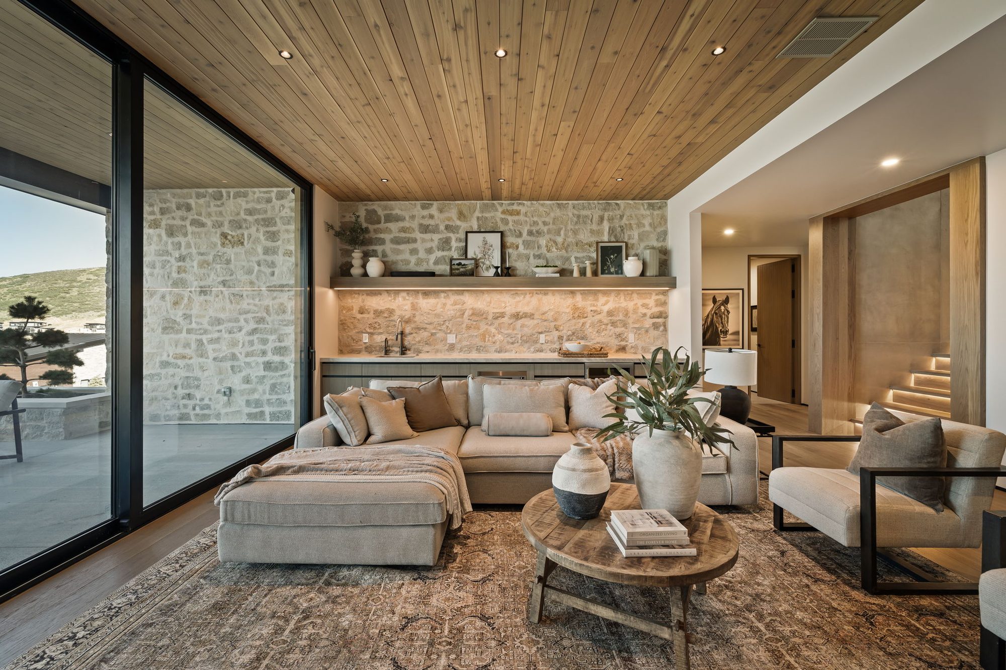 Lumen — great room opening to a glass wall and the valley beyond