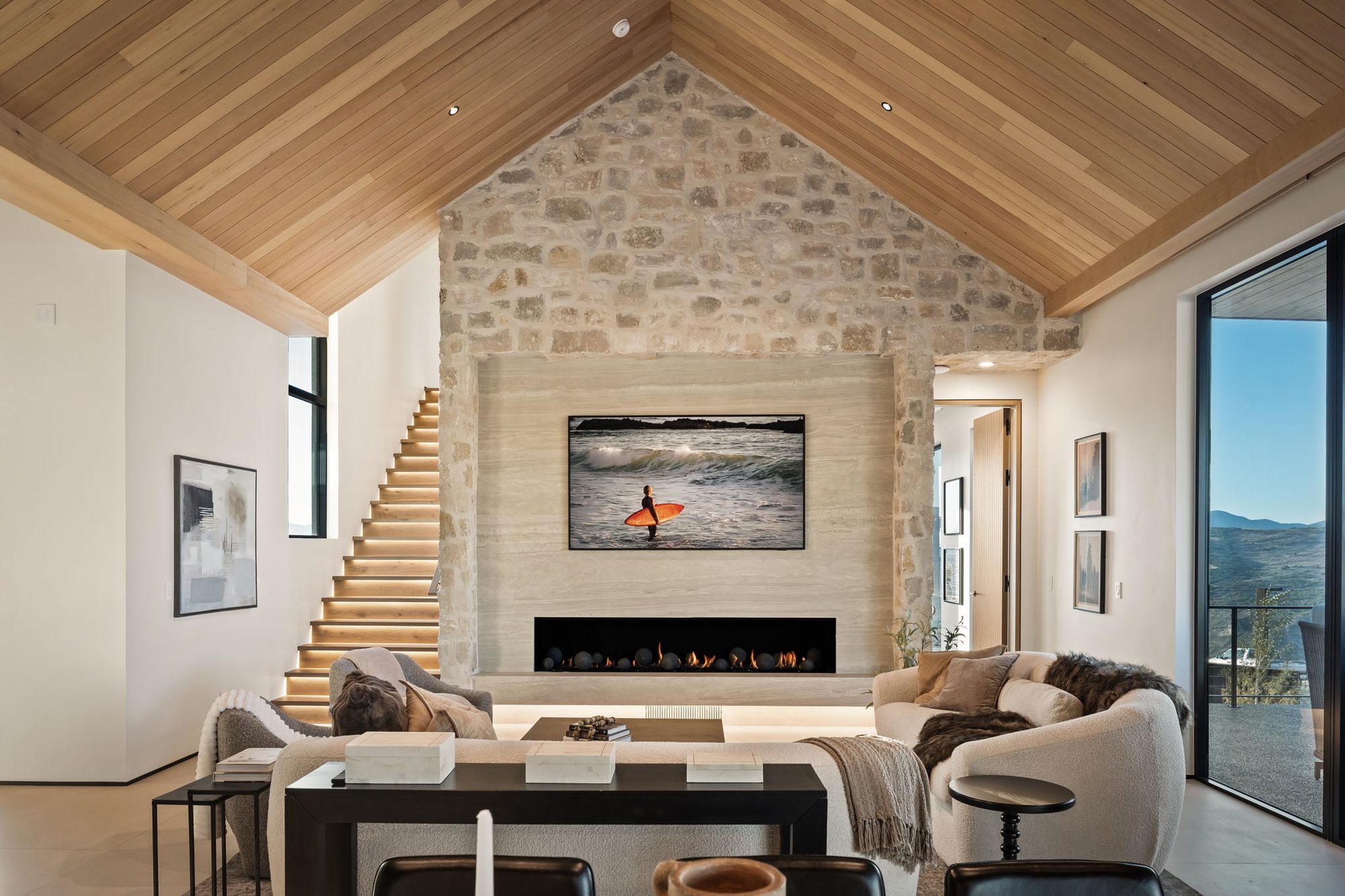 Lumen great room with stone fireplace and glass at both ends