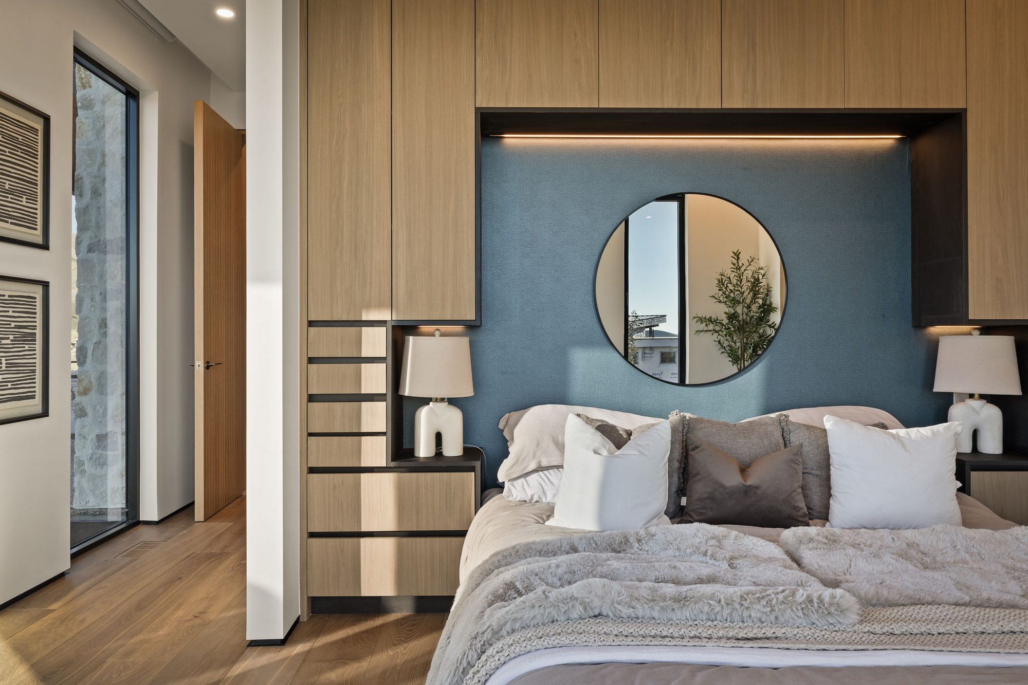 Lumen — guest bedroom with a deep blue accent wall and round mirror