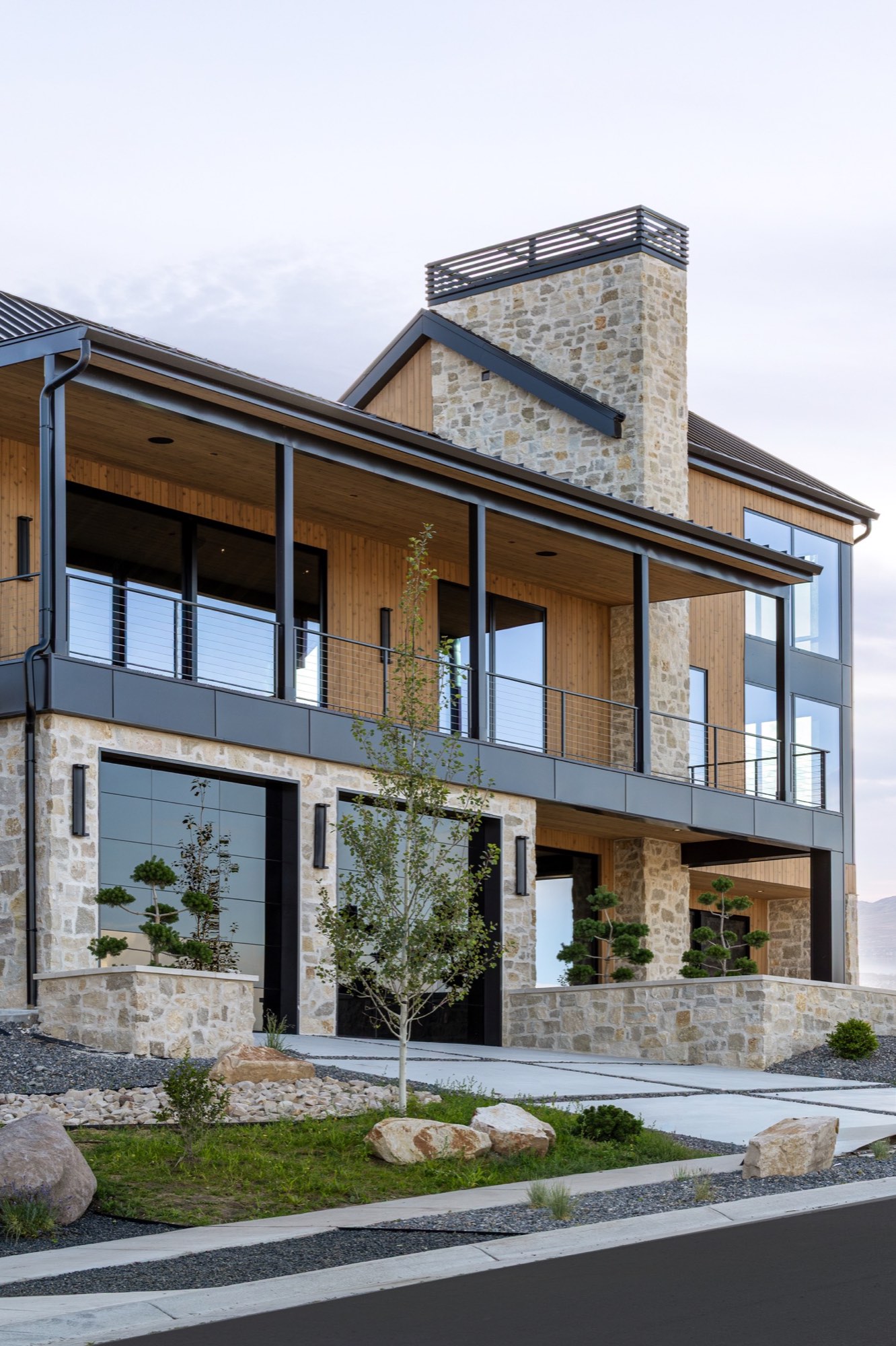 Lumen — covered deck over stone base at dusk with sculpted evergreens