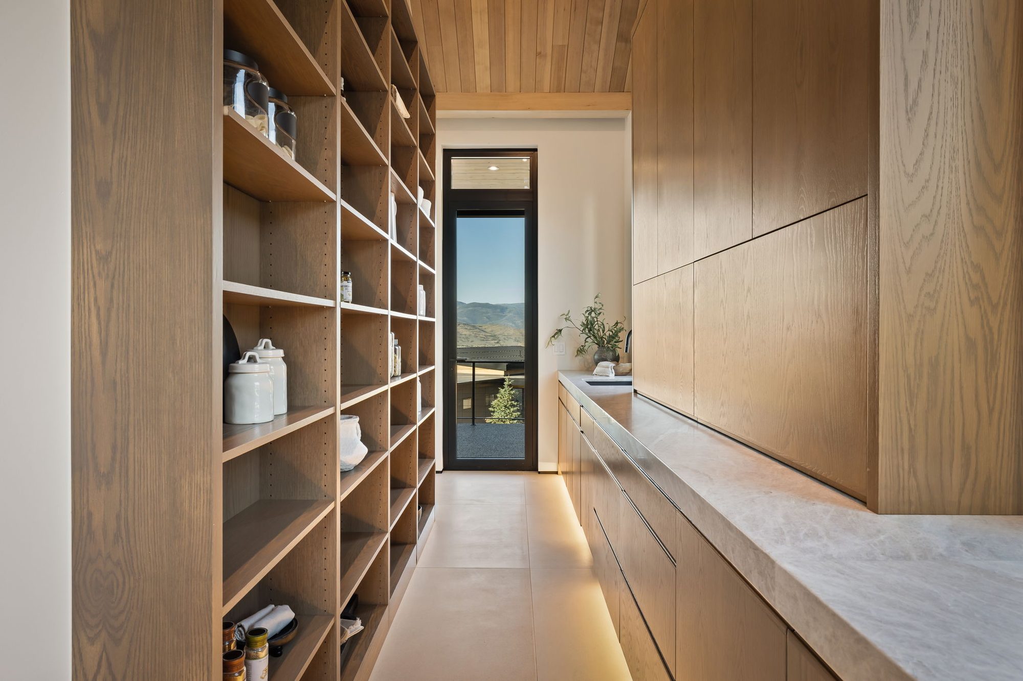 Lumen — scullery with floor-to-ceiling white oak shelving and a stone counter
